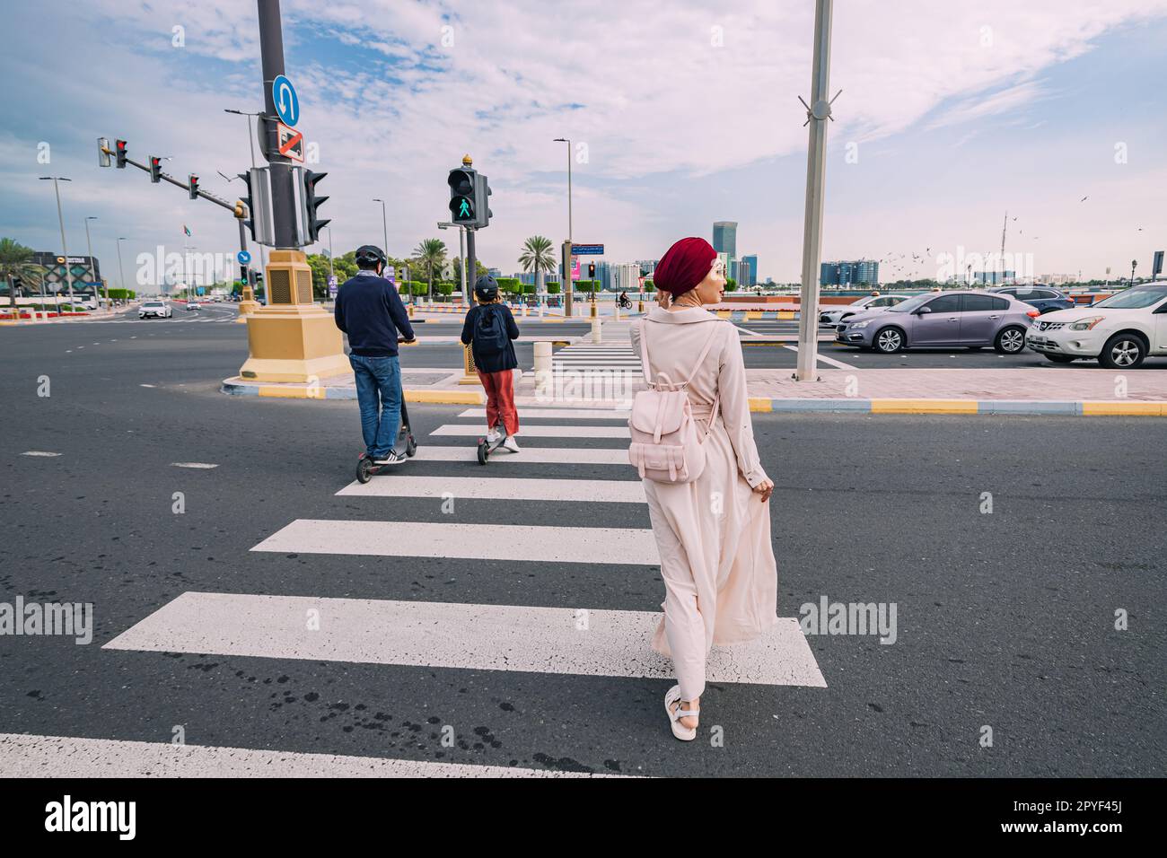 15 January 2023, Abu Dhabi, UAE: scooters and girl crosses the road at