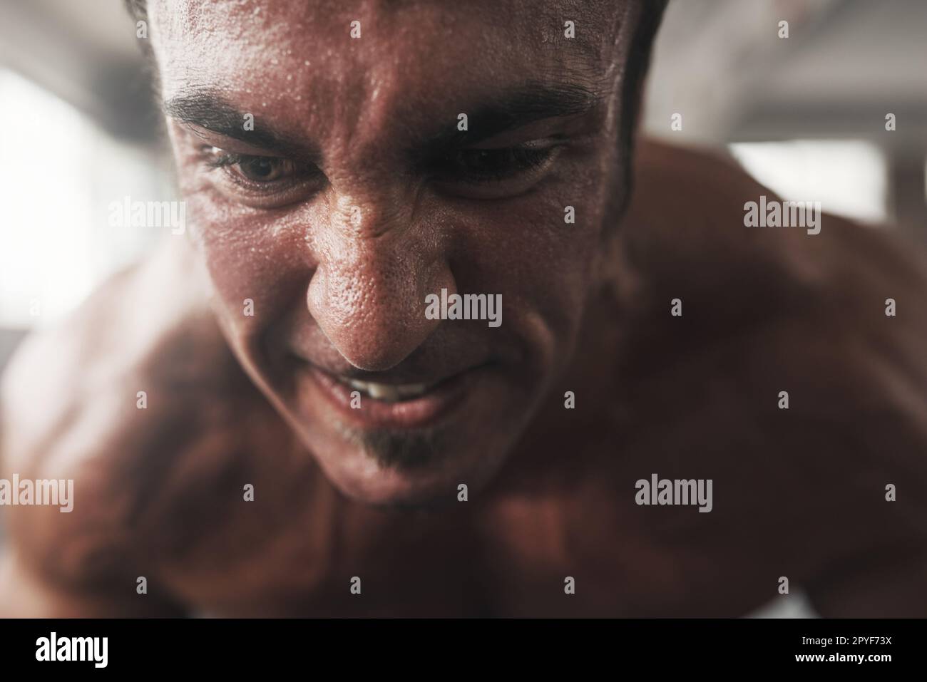 You are stronger than your challenges. Closeup shot of a muscular young man working out in a gym. Stock Photo