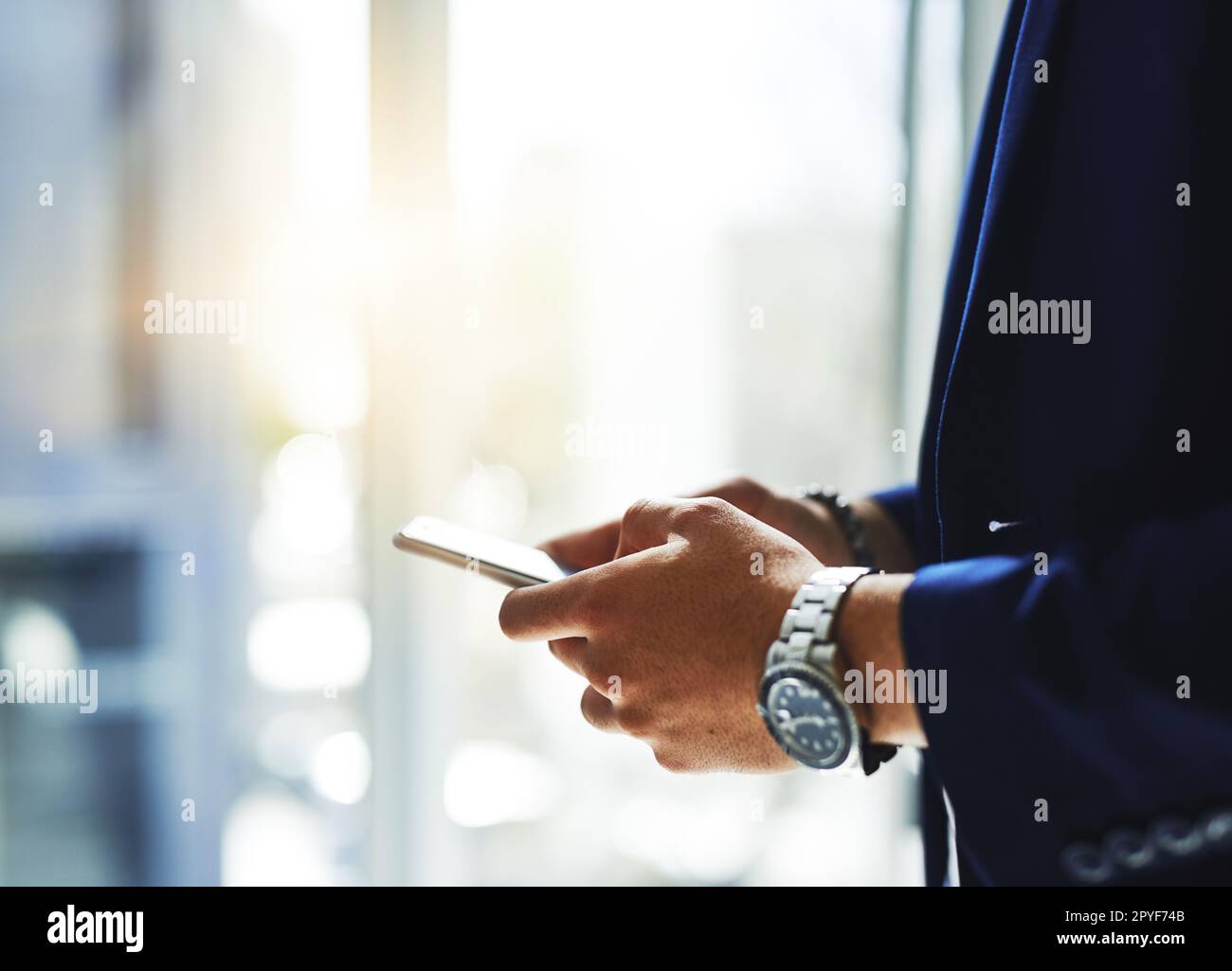 Dial his number and make those numbers. a businessman using a mobile phone in a modern office. Stock Photo