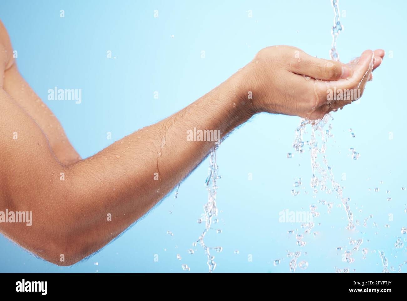 Man, water or washing hands on blue background for body hygiene maintenance, healthcare wellness or skincare grooming routine. Model, water splash or running shower for cleaning bacteria or self care Stock Photo