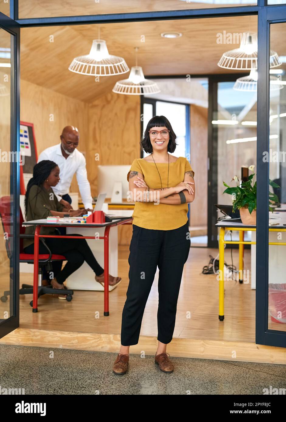 Go after your dreams. a creative businesswoman standing in her office with colleagues blurred in the background. Stock Photo