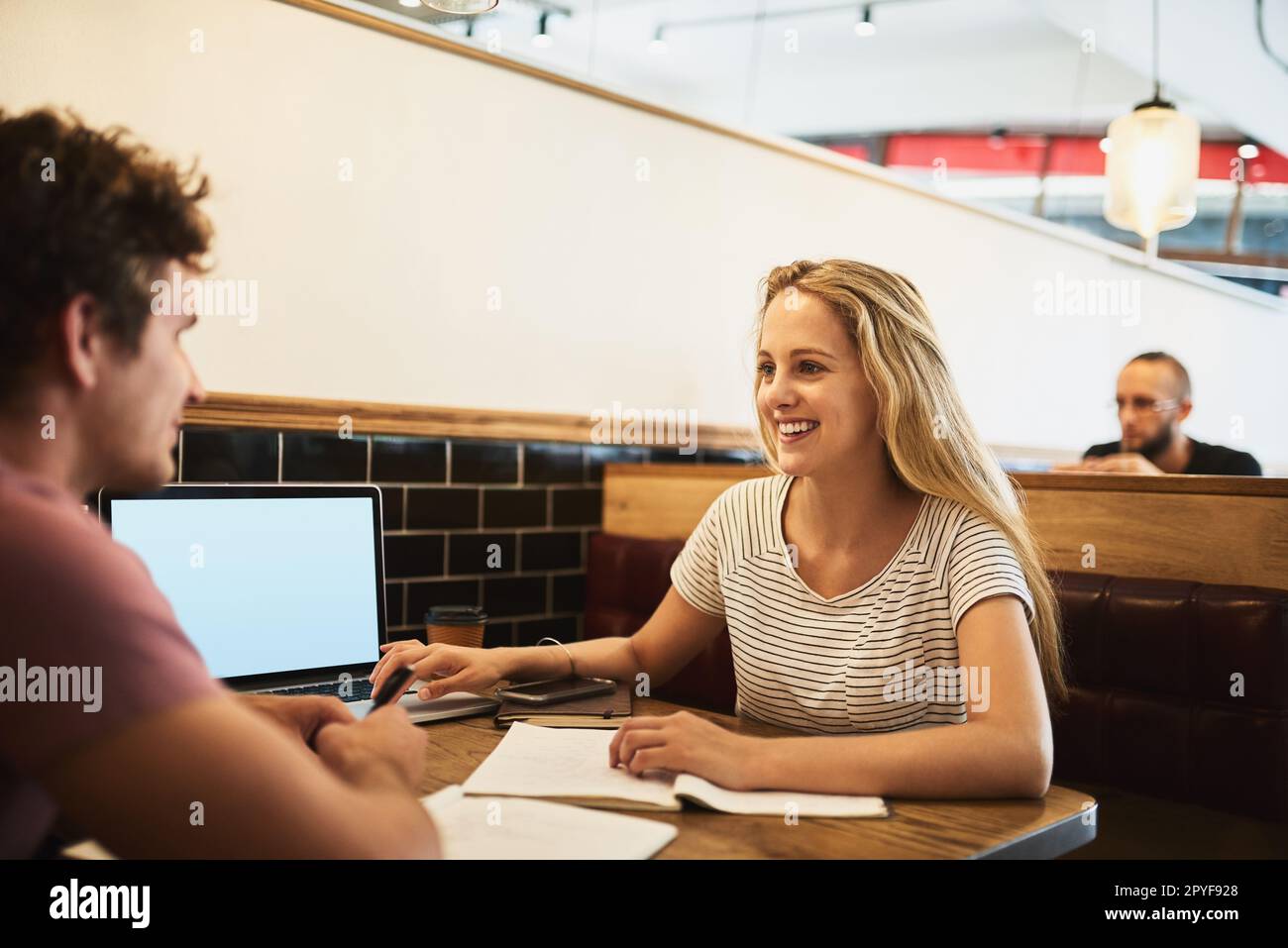 Technology and tutoring elevate her studies. two happy young students having a study session at their favorite cafe. Stock Photo
