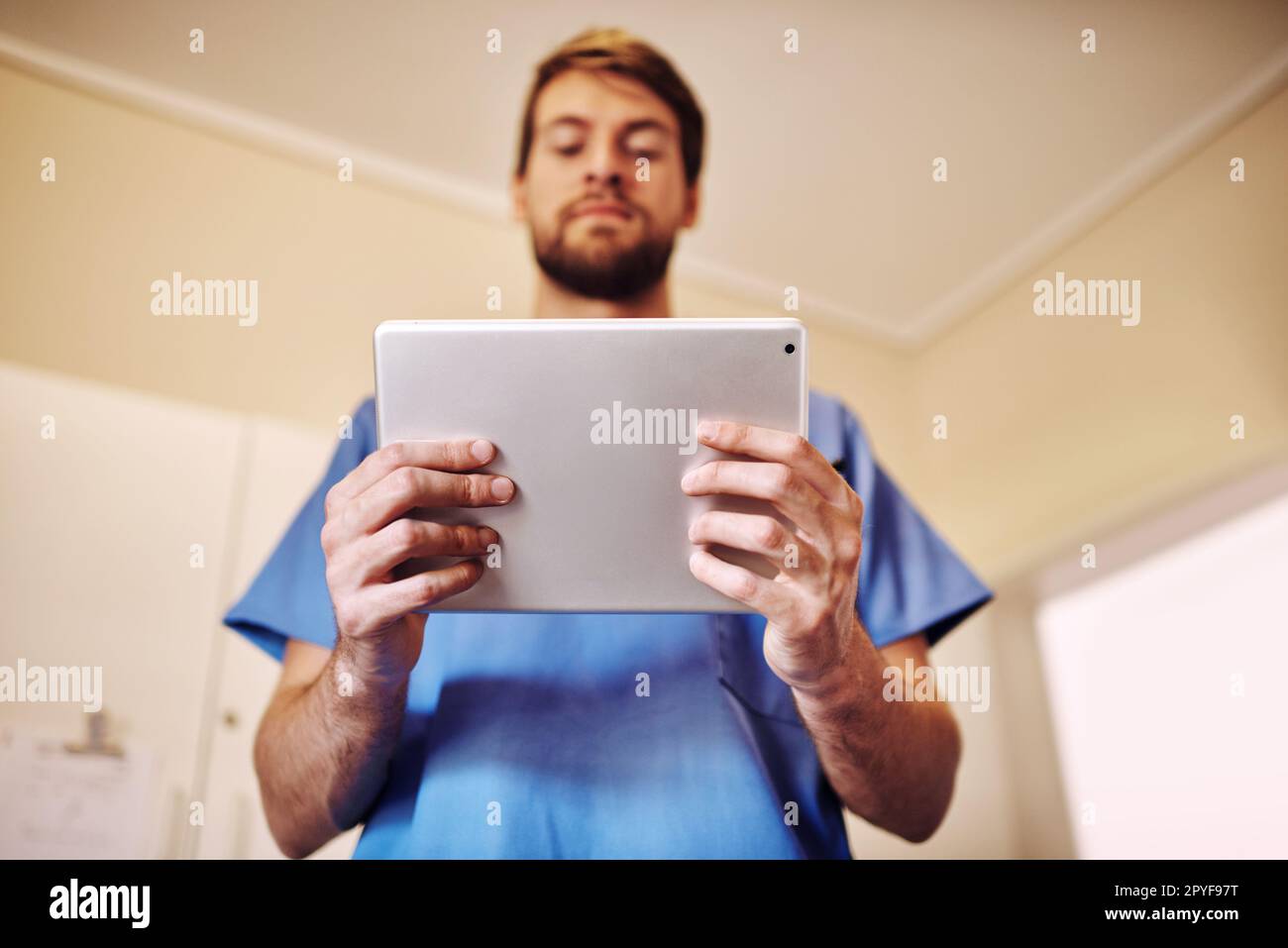 Good doctors always do their research. a young doctor using his digital tablet in his office. Stock Photo