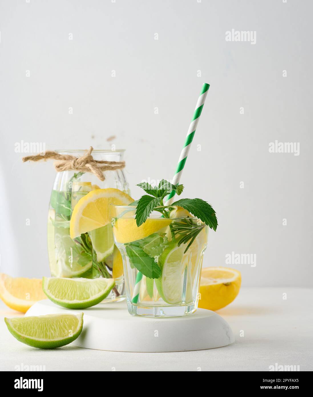 https://c8.alamy.com/comp/2PYFAX5/lemonade-in-a-transparent-glass-with-lemon-lime-rosemary-sprigs-and-mint-leaves-on-a-white-background-2PYFAX5.jpg