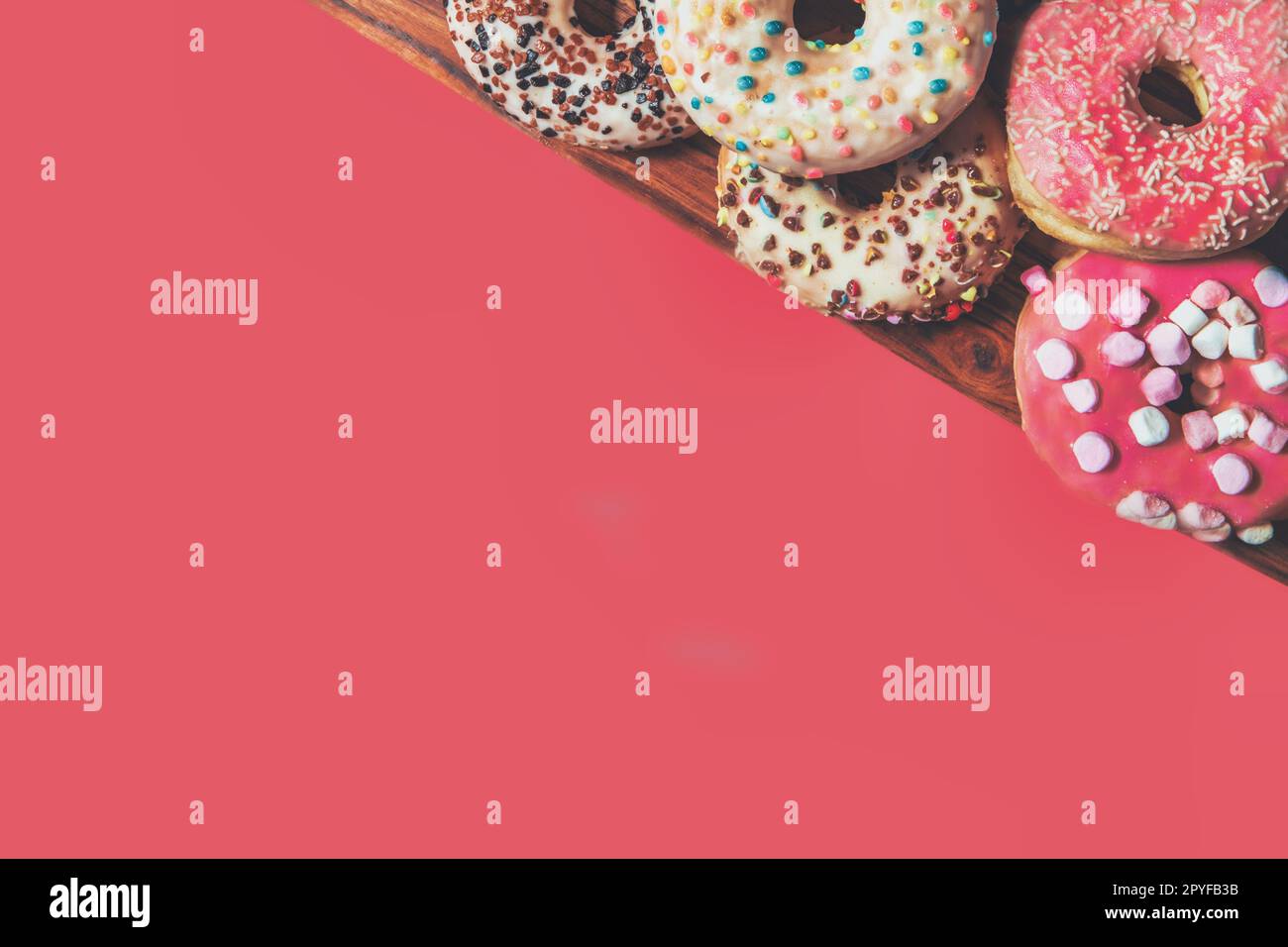 Donuts with sprinkles on pink background. Sugar, calories, homemade sweets concept. Stock Photo