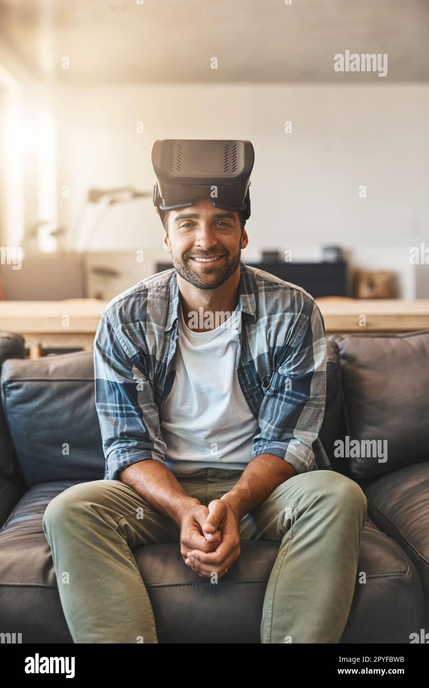 Technology, bringing the future of film into the home. a young man using a virtual reality headset on the sofa at home. Stock Photo