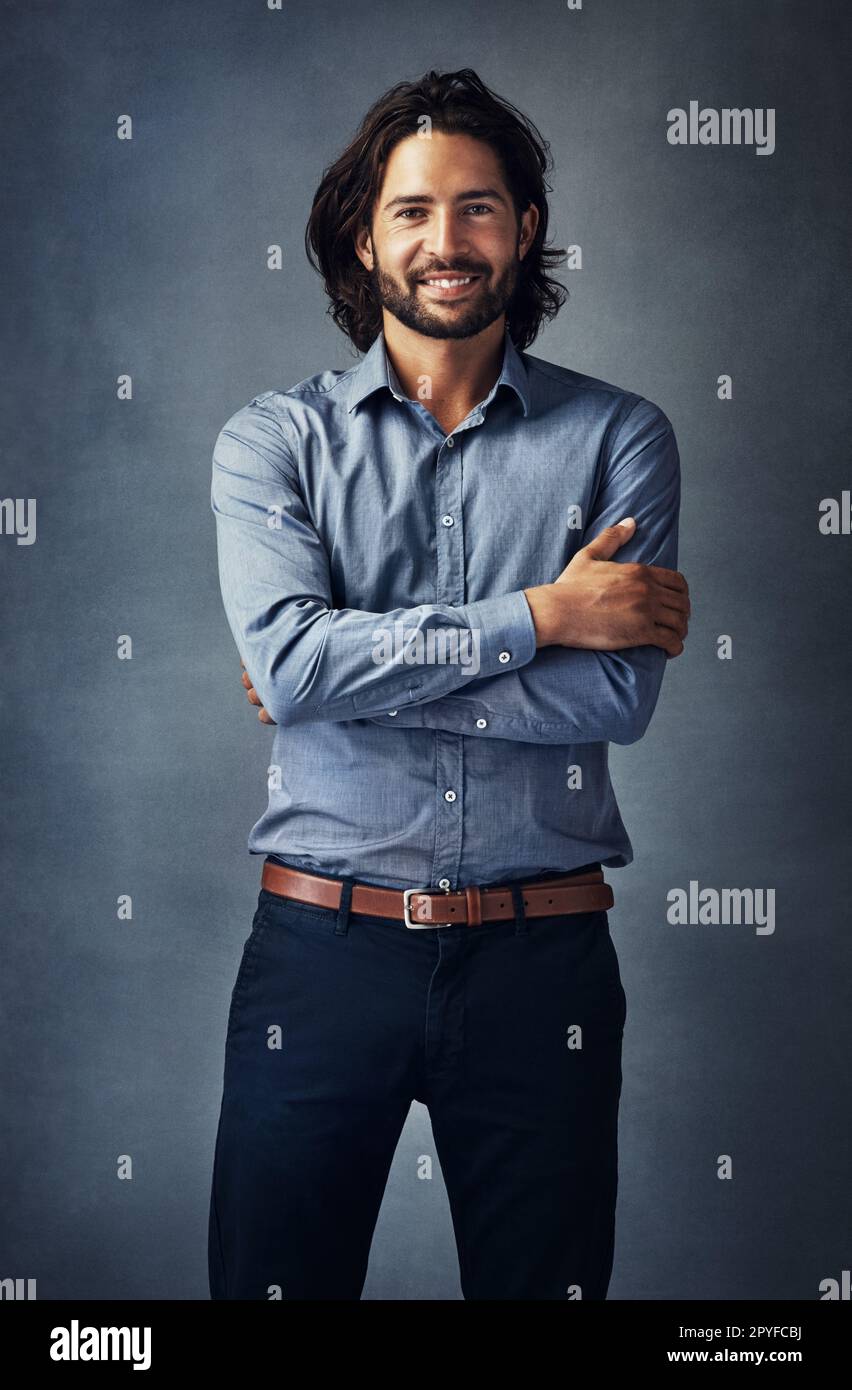 Confidence is an attractive quality on a man. Studio portrait of a handsome young man standing with his arms folded against a grey background. Stock Photo