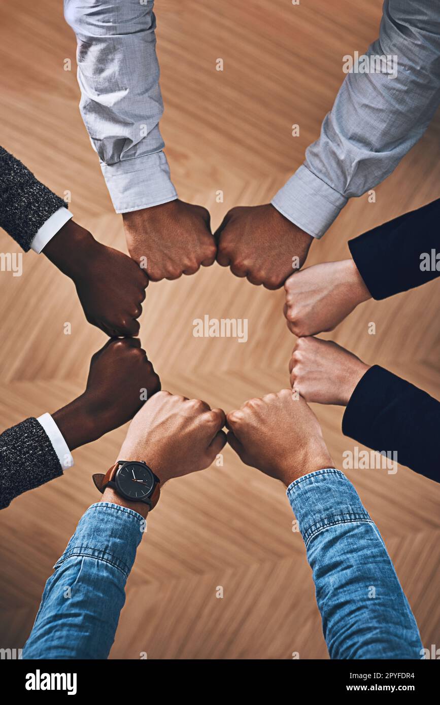 Challenges are easier to defeat together. High angle shot of a group of unidentifiable businesspeople joining their hands together in a unity. Stock Photo