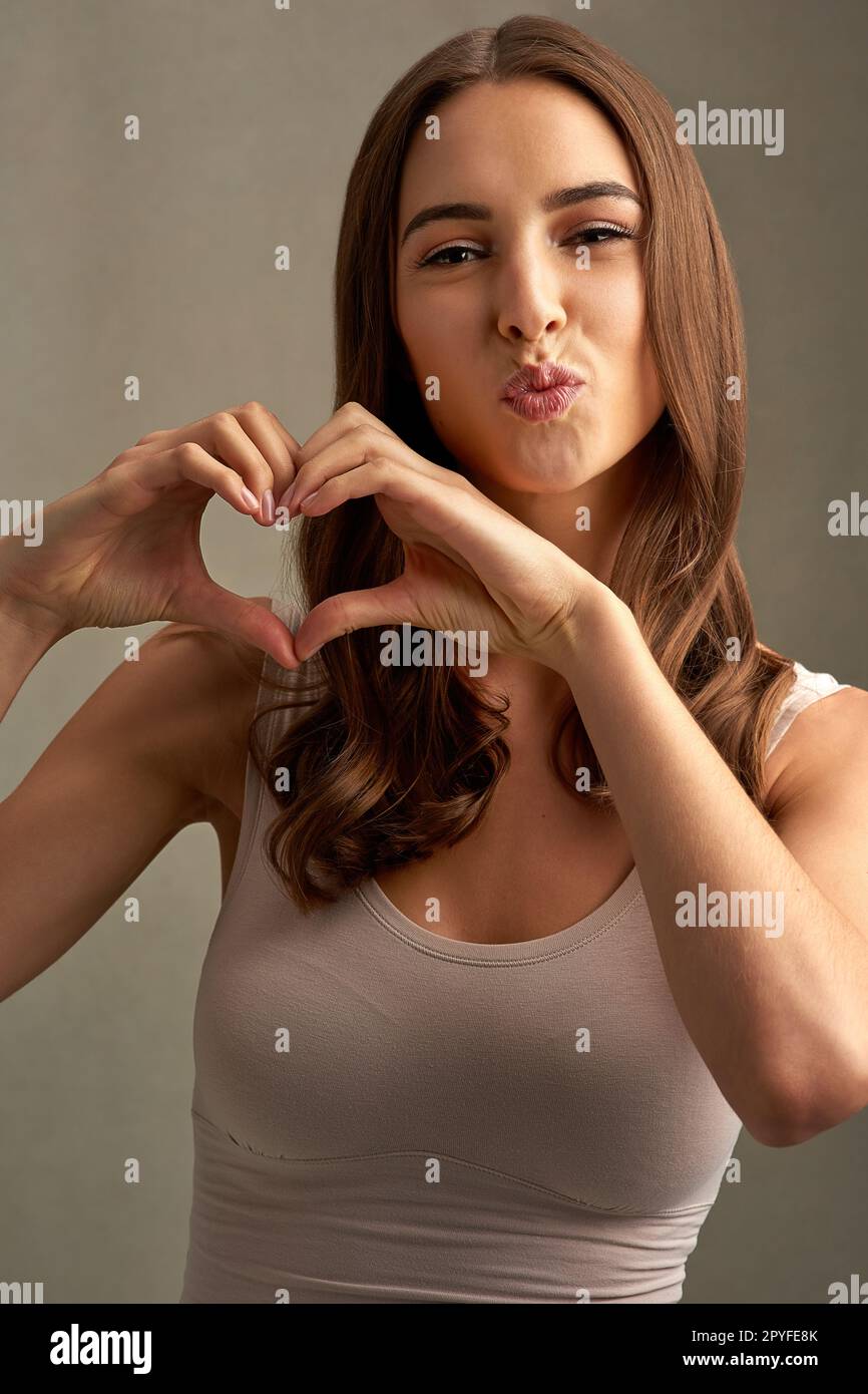 Filled with love. Studio portrait of an attractive young woman making a heart shape with her hands. Stock Photo