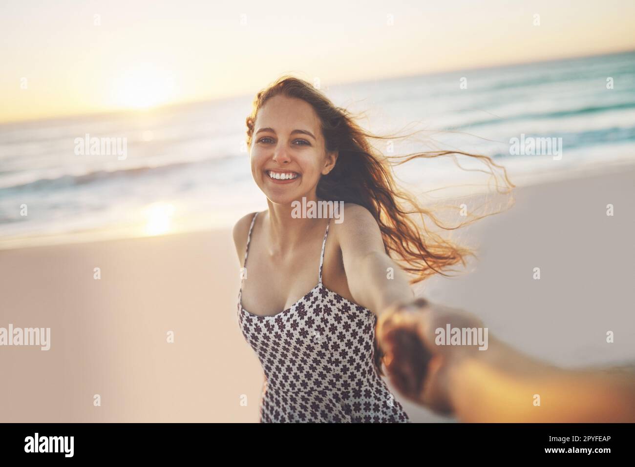 Paradise is never too far away. a young woman pulling someones hand at the beach. Stock Photo