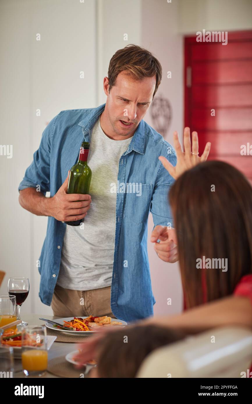 Now you listen to me. a drunk man and his wife arguing in front of their children during lunch. Stock Photo