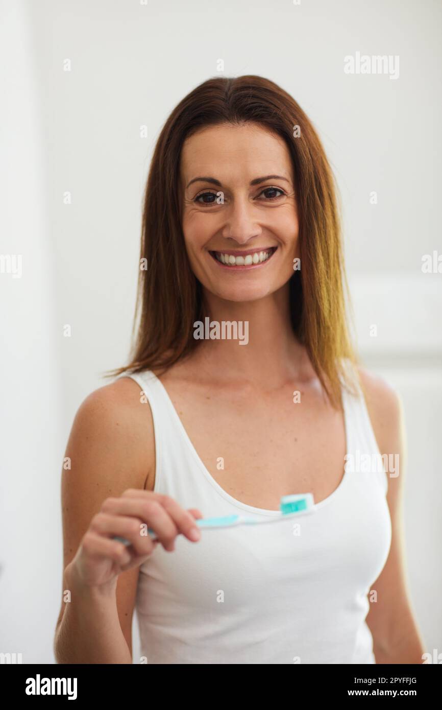 Make it a habit. Portrait of a woman brushing her teeth in the bathroom. Stock Photo