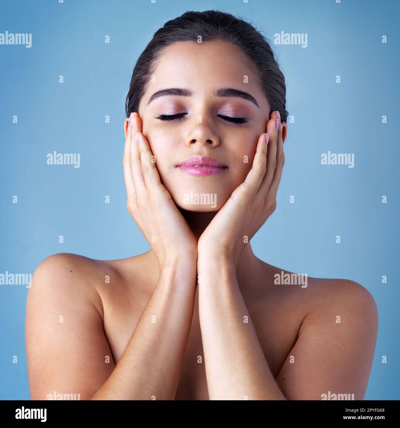 Shes in love with her new skincare regime. Studio shot of a beautiful young woman posing against a blue background. Stock Photo