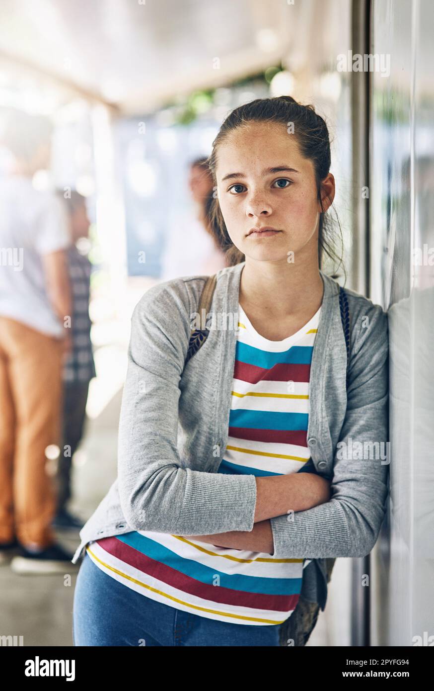School can be a lonely place. Portrait of a lonely schoolgirl standing outside her classroom