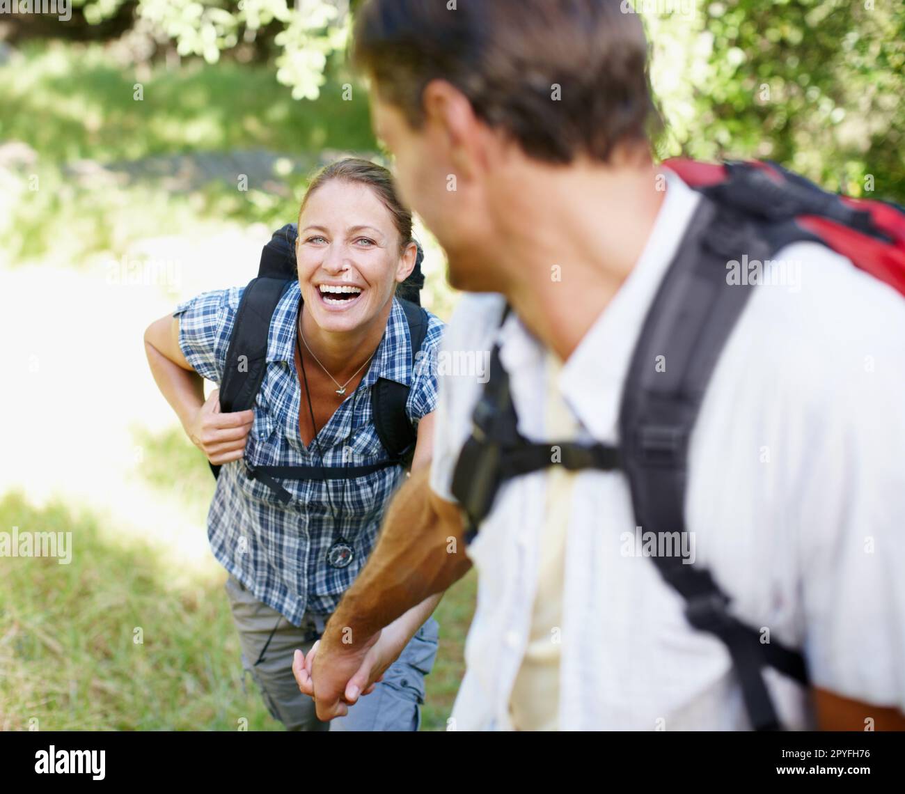 Ill go anywhere with you by my side. A young couple holding hands while hiking with their backpacks. Stock Photo