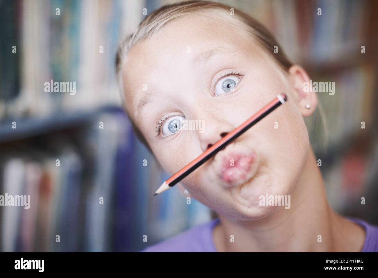 Studying can be a balancing act. A cute young girl balancing her pencil on her lips and pulling a face. Stock Photo