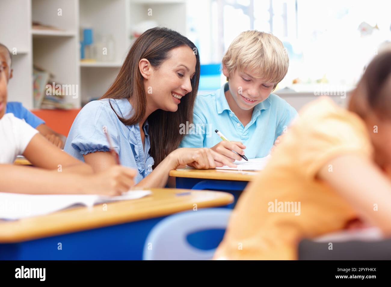 Ill help you. A happy young teacher helping out a student with his work. Stock Photo