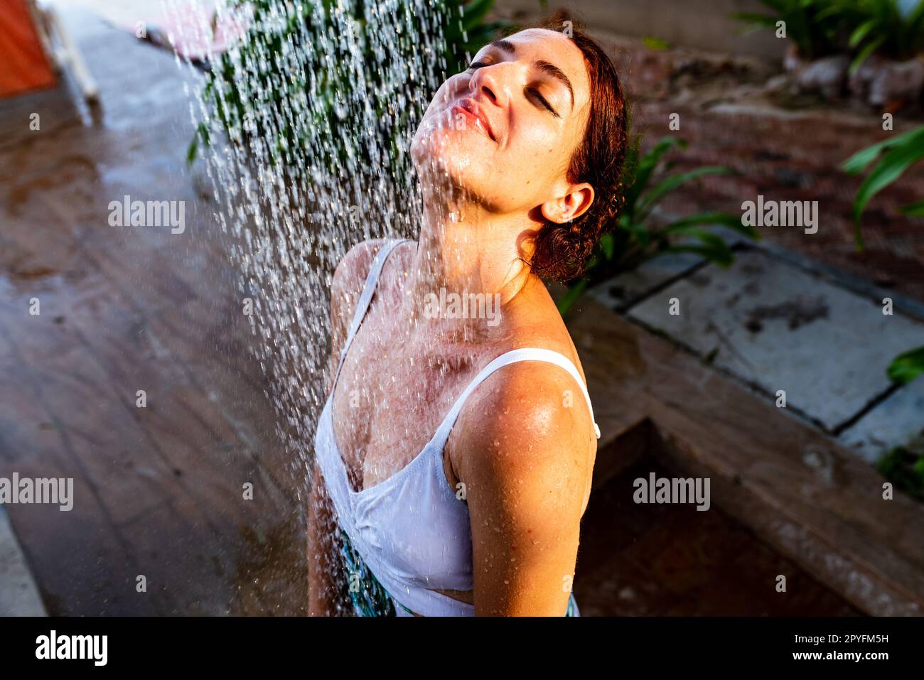 Woman taking an outdoor refreshing shower at a dream vacation resort
