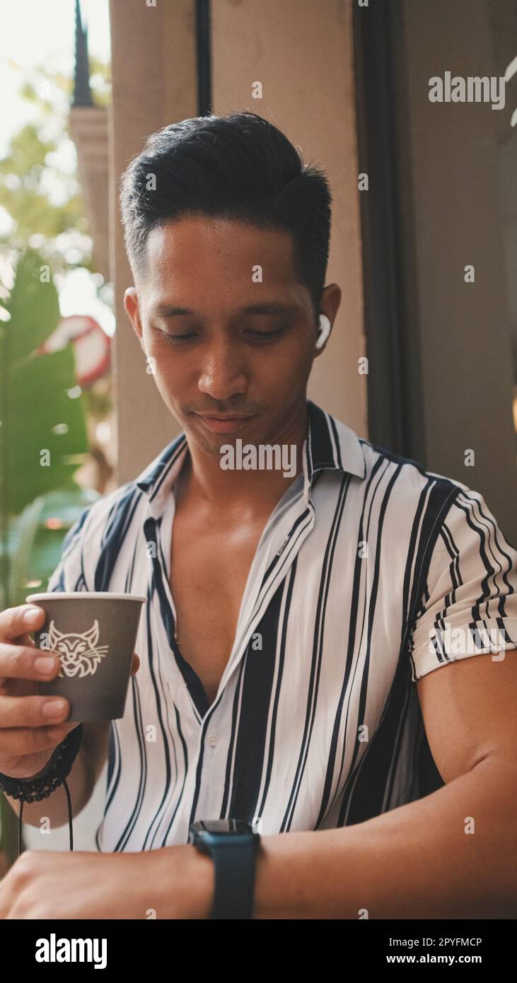 Young man sits outside and drinks coffee Stock Photo