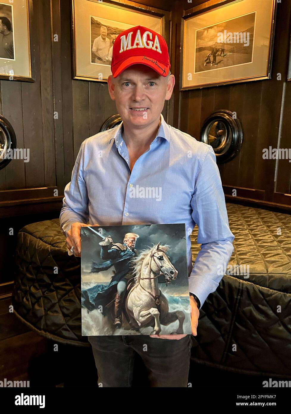 Tadhg O'Shaughnessy, supporter of former US president Donald Trump, wearing a MAGA hat and carrying a fan-made portrait of the former president riding a horse, Mr O'Shaughnessy said being a Trump supporter was like being a fan of Elvis. Mr Trump arrived at Trump International Golf Links & Hotel in Doonbeg, Co. Clare, during his visit to Ireland. Picture date: Wednesday May 3, 2023. Stock Photo