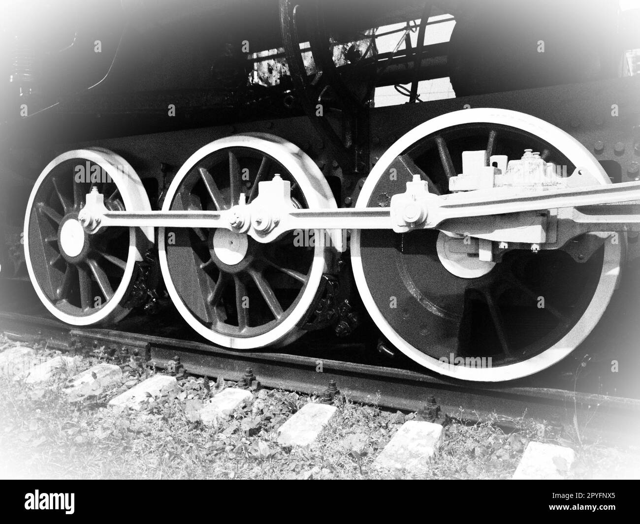 Retro train wheels. Beautiful card. Sleepers and rails, pistons and guides. Locomotive of the 19th early 20th century with steam engine. Vintage style. Black-white. White vignetting around the edges Stock Photo