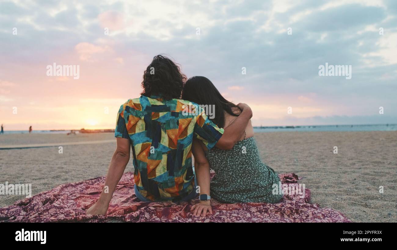 Man and woman hugging each other by the beach and watching the dawn ...