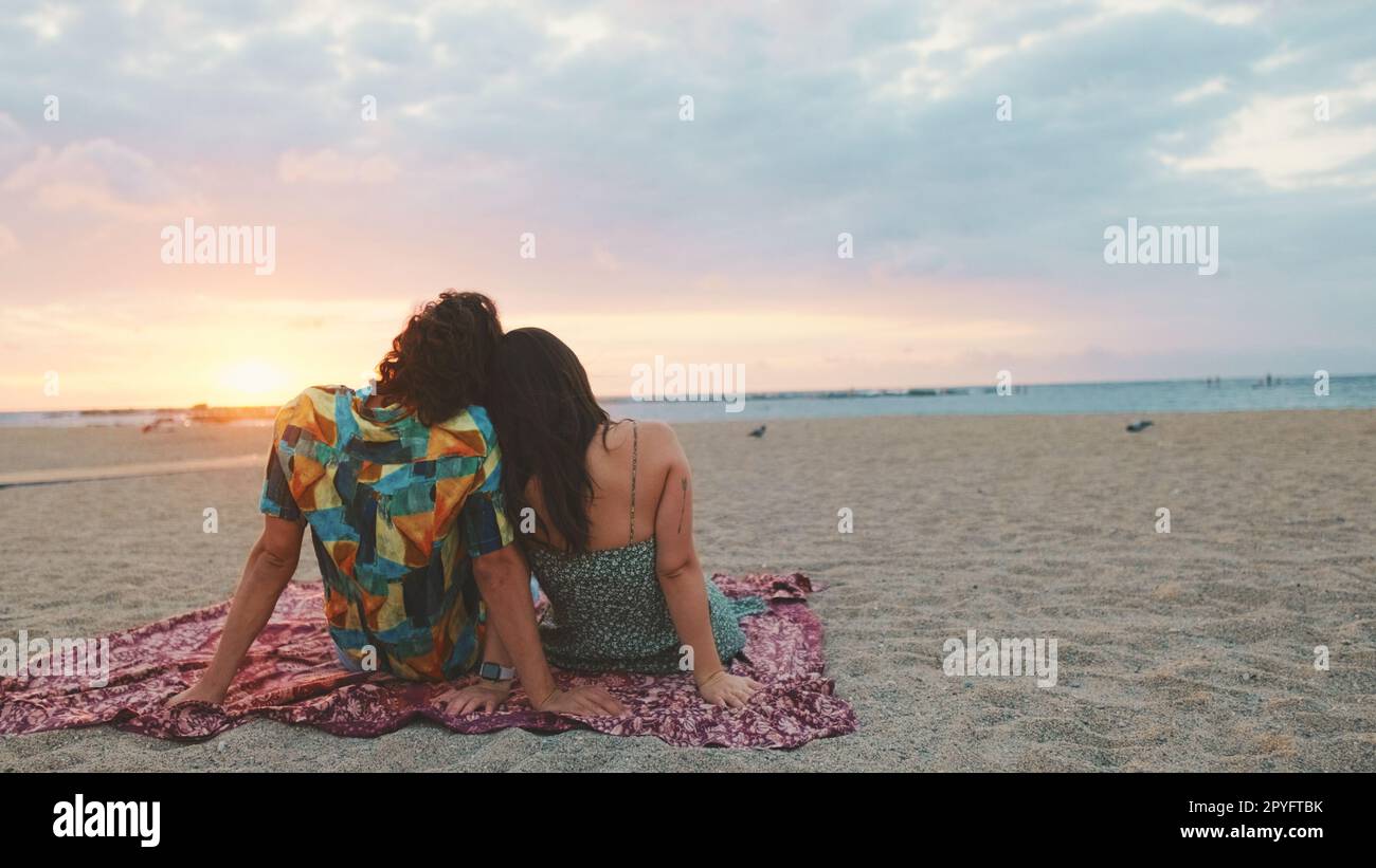 Man and woman hugging each other by the beach and watching the dawn ...