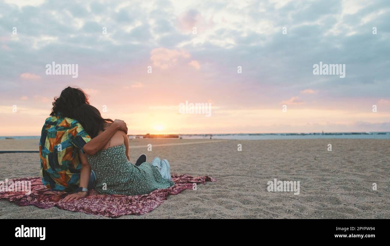 Man and woman hugging each other by the beach and watching the dawn ...