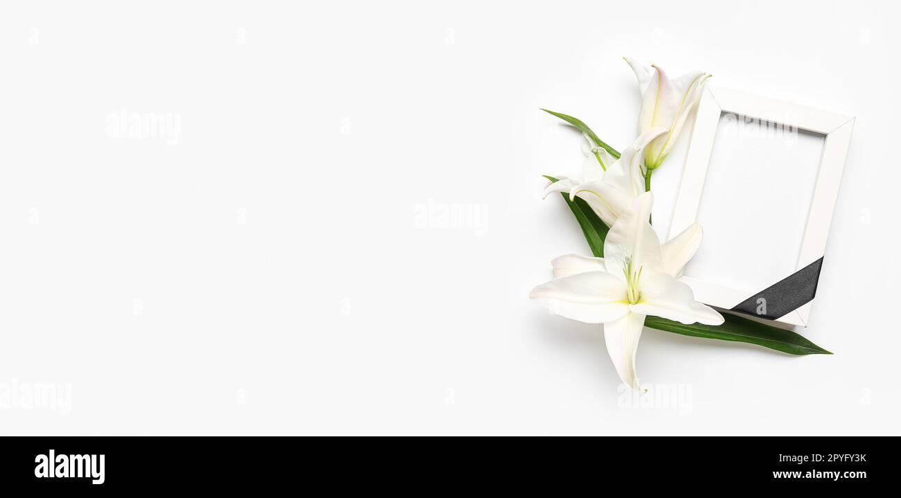 Blank funeral frame and lily flowers on white background with space for