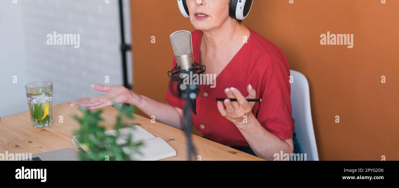 Banner Close up woman making podcast recording for her online show. Attractive business woman using headphones front of microphone for a radio broadcast Stock Photo