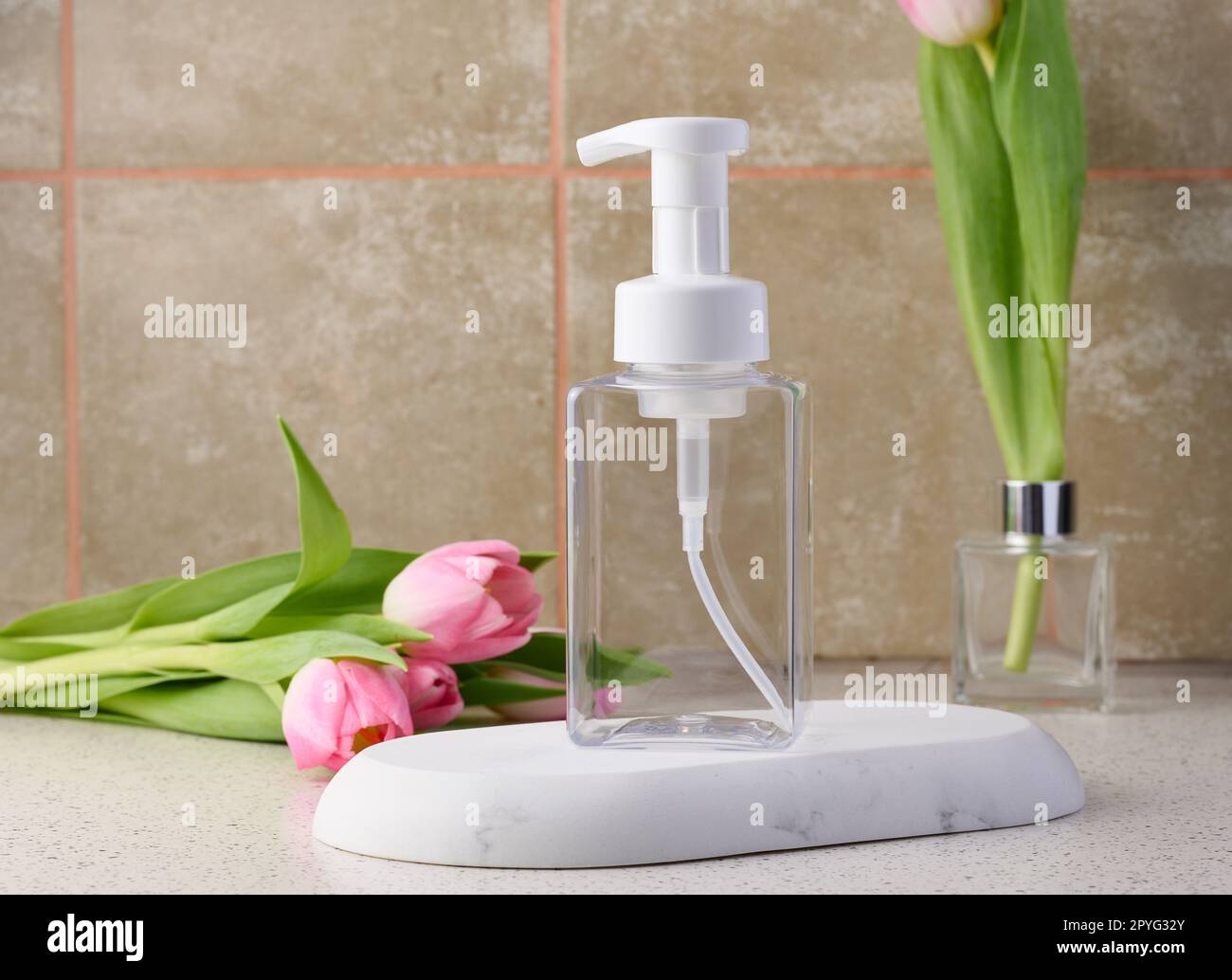 Transparent plastic container with a dispenser on the table. Bottle for liquid soap, shampoo Stock Photo