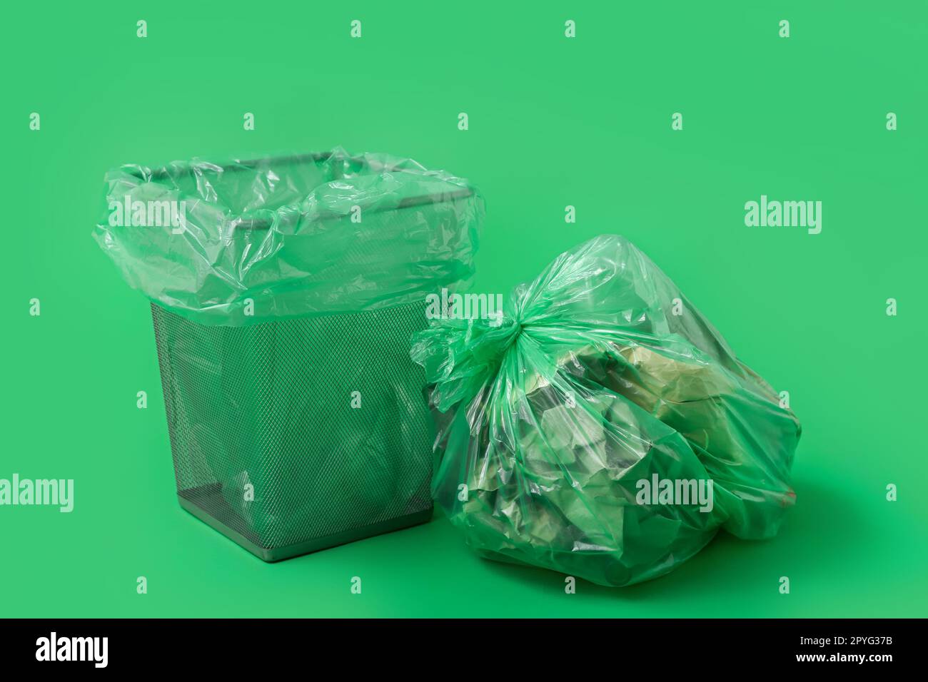 Empty trash bin and full garbage bag on green background Stock Photo Alamy