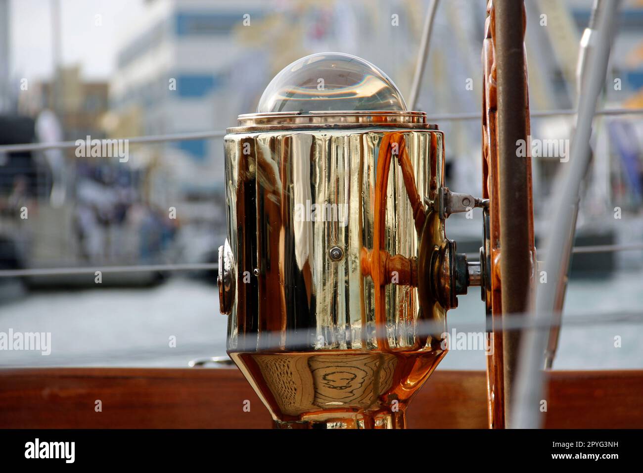 A golden old style compass detail on a boat against a backdrop of boats