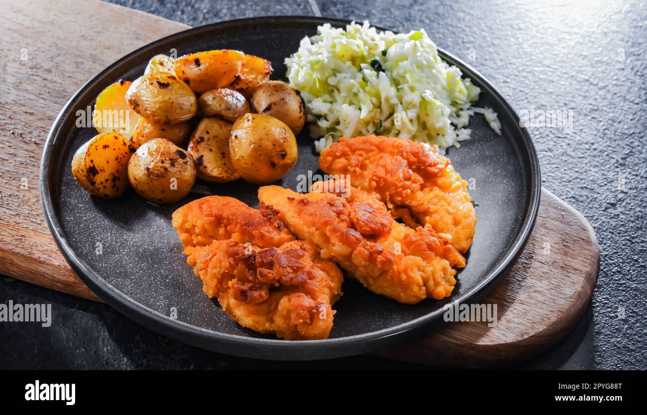 Breaded chicken cutlets served with potatoes and cabbage Stock Photo