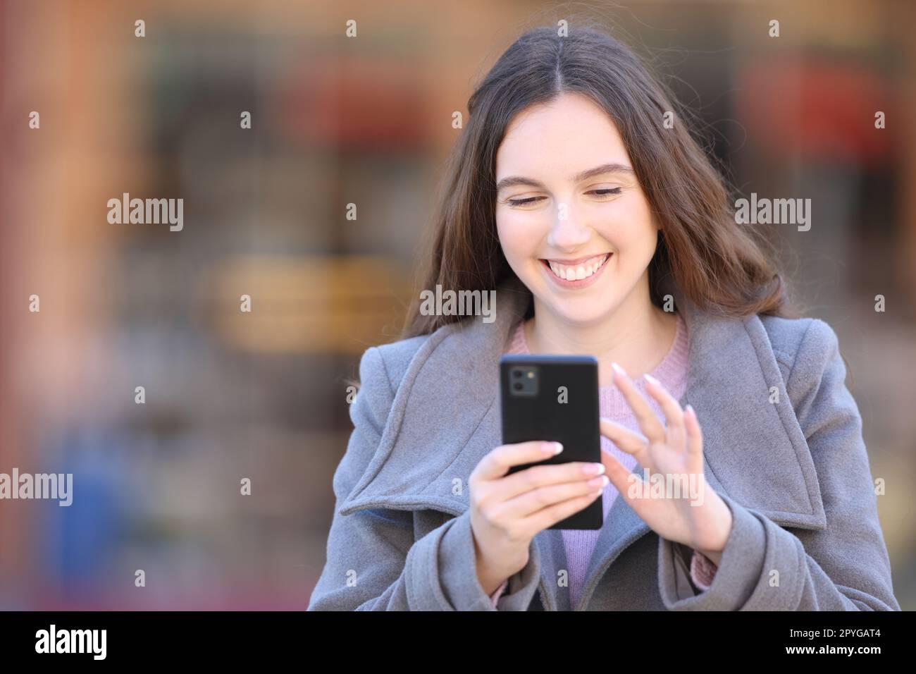 Happy woman walks checking phone in winter Stock Photo