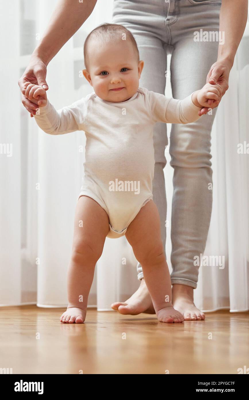 happy little baby girl learning to walk with mother help Stock Photo