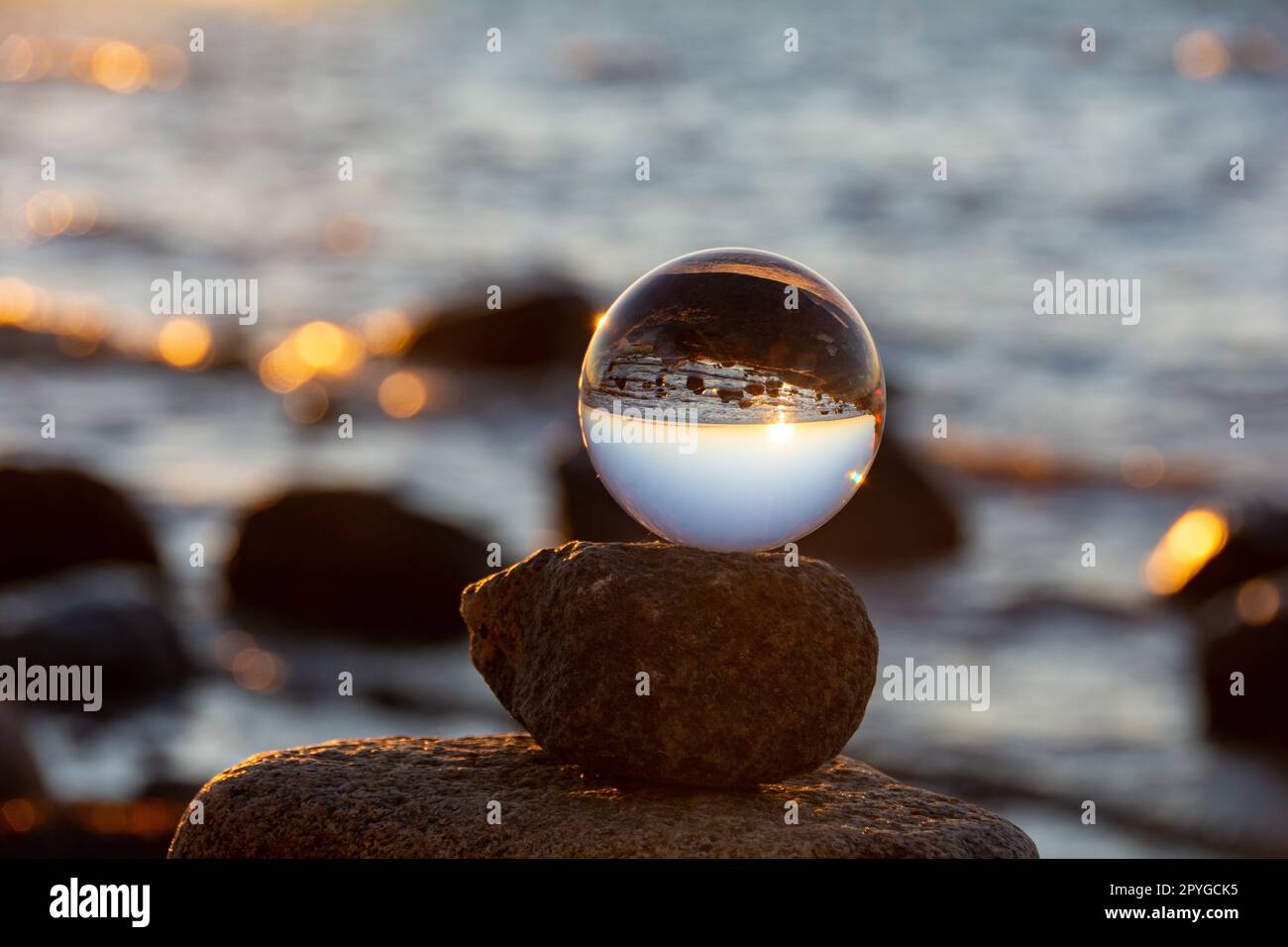The glass ball lies on the top stone reflecting the beach and the sea ...