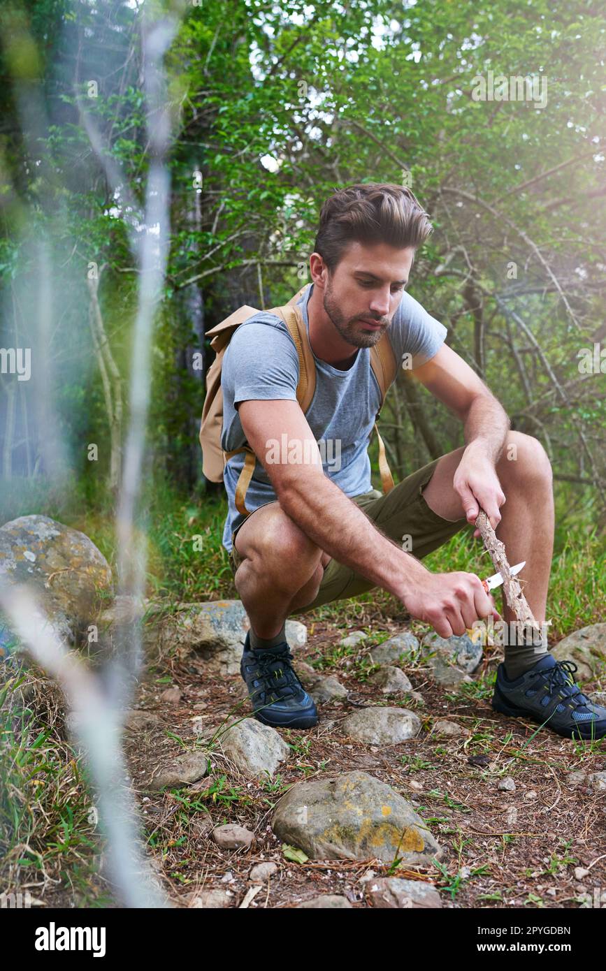 Getting ready for sunset. a handsome hiker whittling a branch. Stock Photo