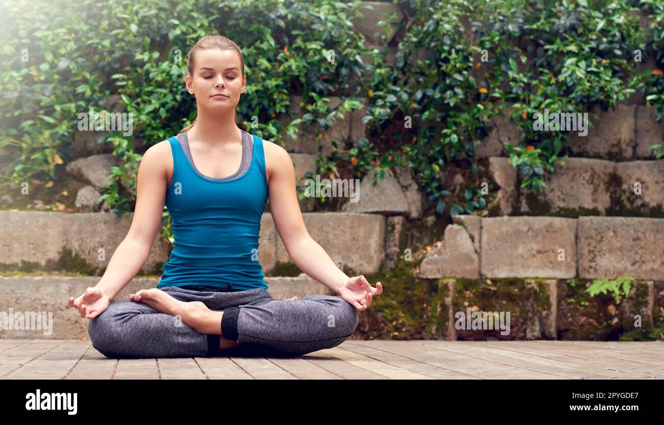 Mindful of her being. a young woman practicing yoga outdoors. Stock Photo