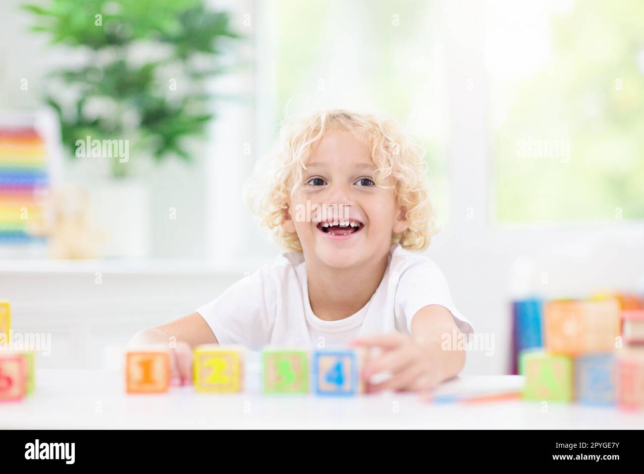 Child learning letters and numbers. Kid with colorful wooden abc blocks
