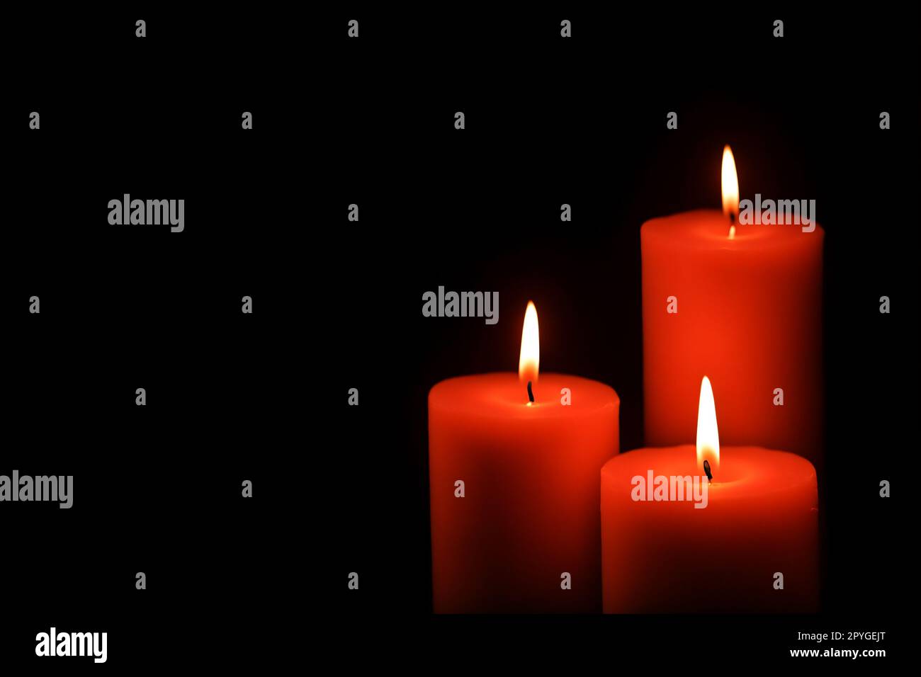 Three red wax candles burning in darkness on dark background Stock ...