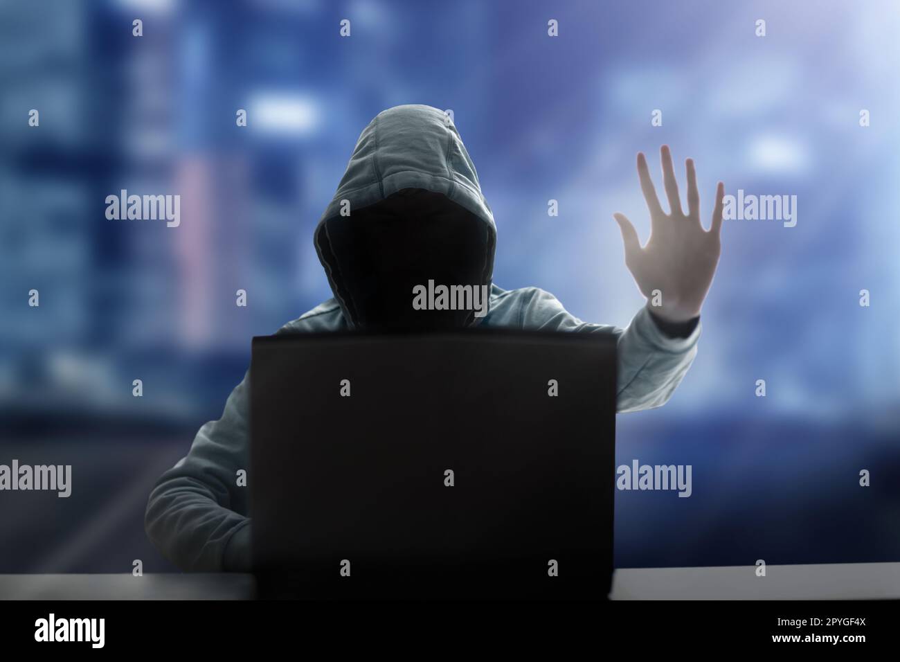 Hacker at laptop. Malware and virus danger. Man in hoodie and dark mask hacking. Dark net and cyber crime. Identity theft. Criminal at work. Stock Photo