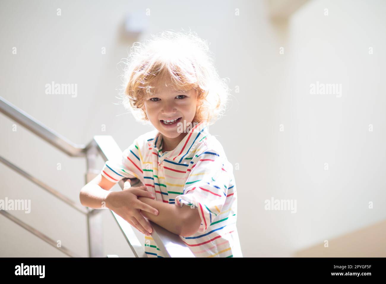 Little boy on stairs. Sunny staircase in new family home. Child