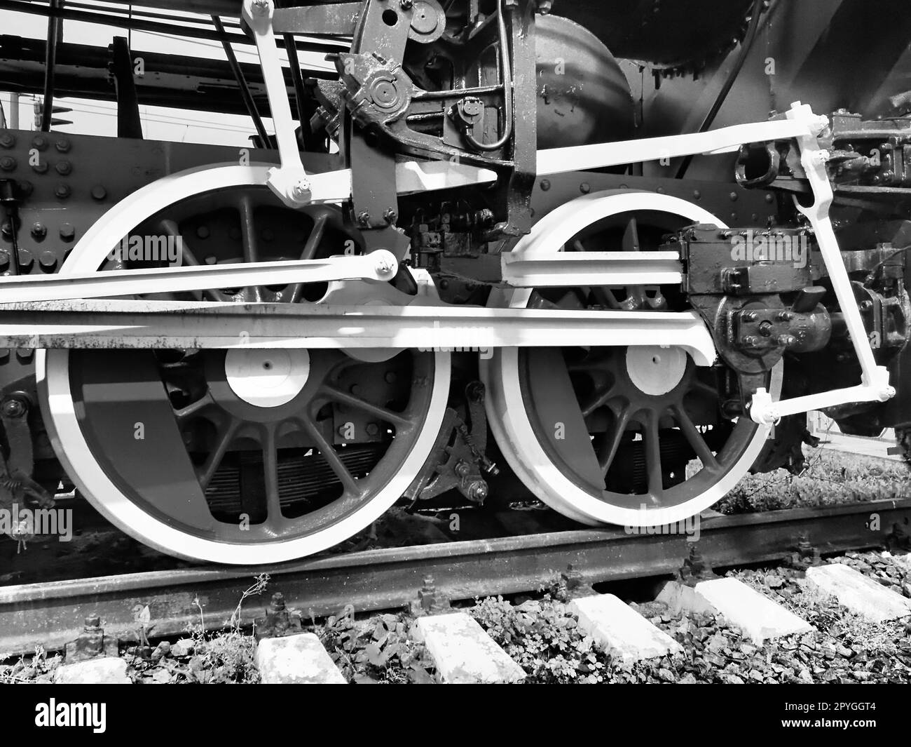 Retro train two wheels. Sleepers and rails, mechanisms, pistons and guides. Locomotive of the 19th early 20th century with a steam engine. Vintage style. Black - white photo. Beautiful card. Stock Photo