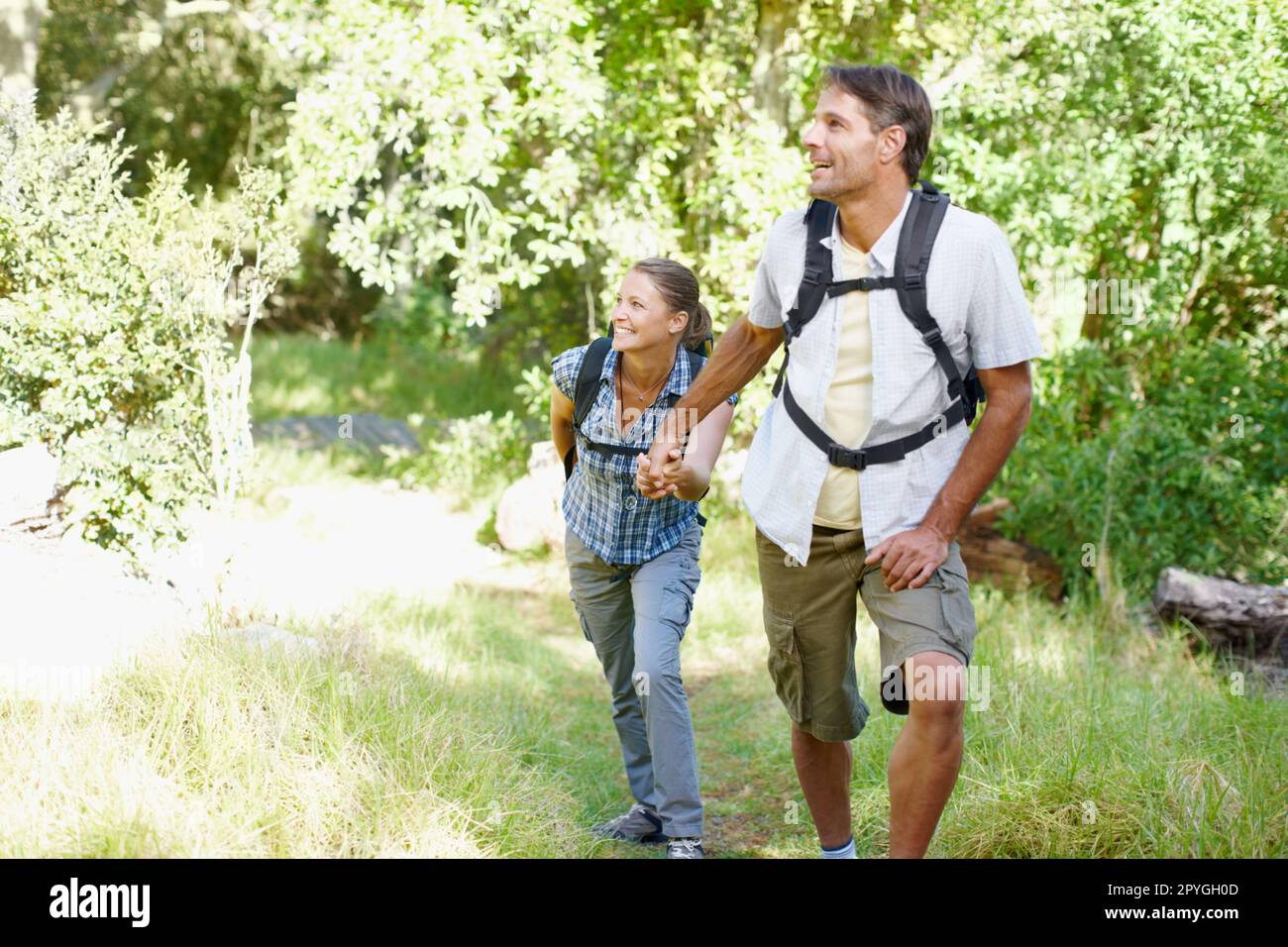 Reliving their first time in the park. A young couple with backpacks walking and holding hands. Stock Photo