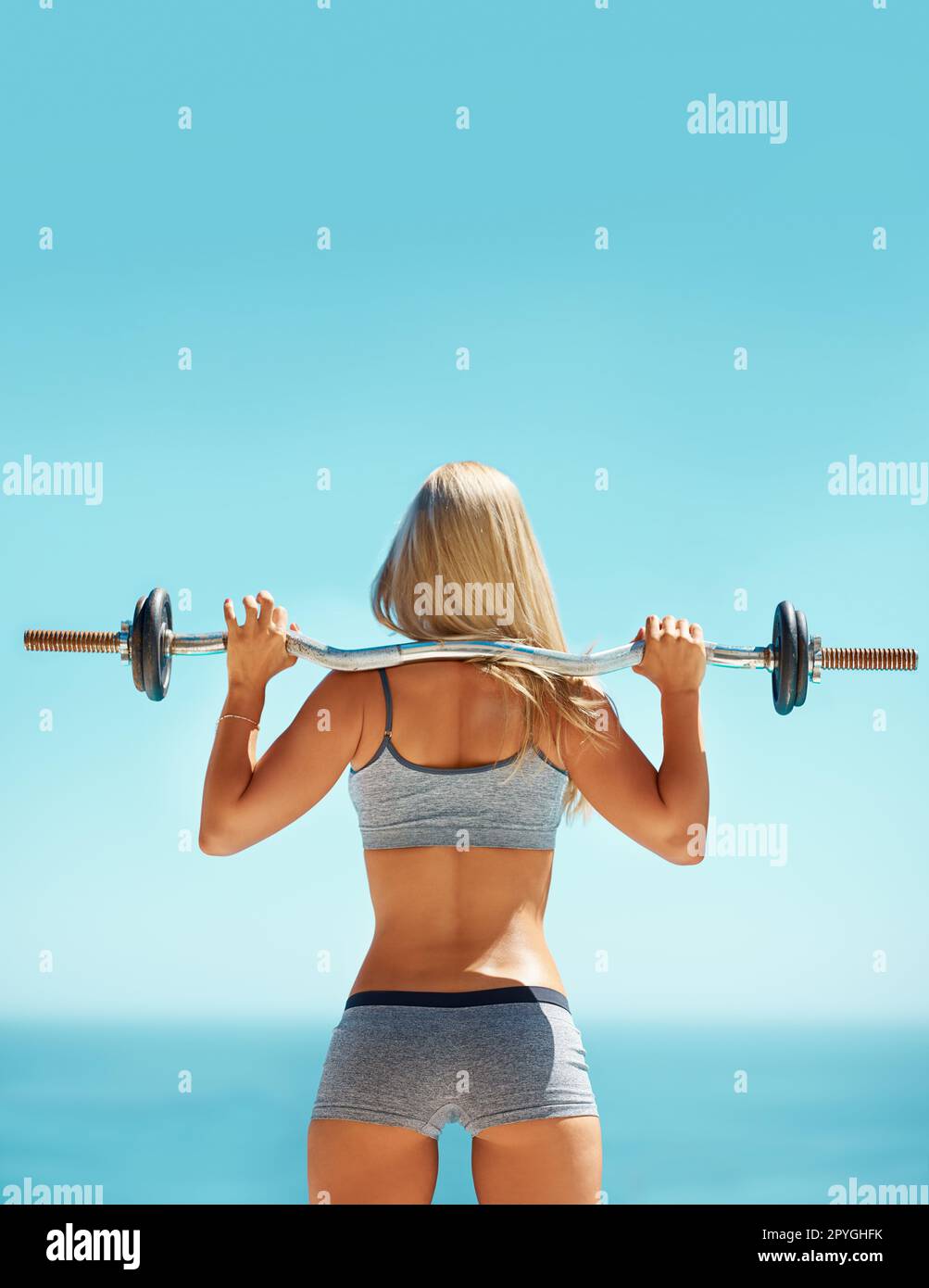 https://c8.alamy.com/comp/2PYGHFK/she-talks-big-but-she-can-back-it-up-rearview-shot-of-a-young-woman-doing-squats-with-a-barbell-outside-2PYGHFK.jpg