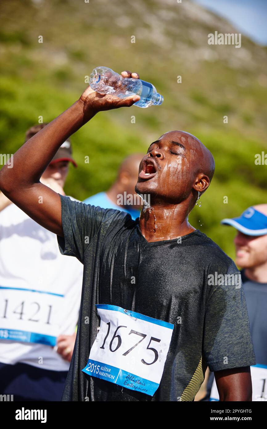 Remember to hydrate. a young male runner pouring water over himself ...