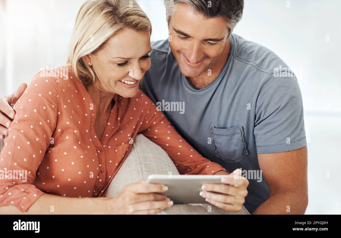 Watch until the end...an affectionate mature couple relaxing with their digital tablet at home. Stock Photo