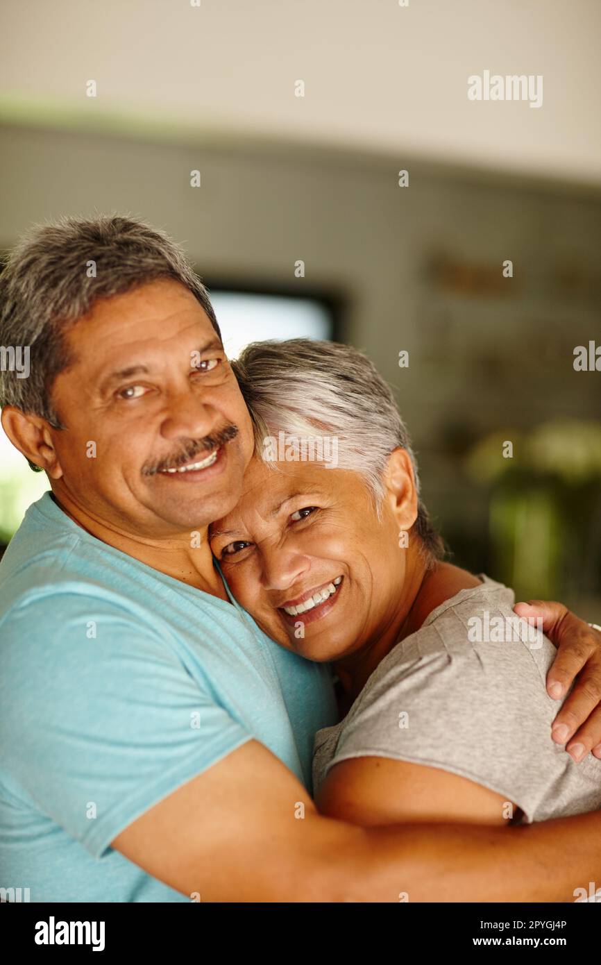 Live your life with love and laughter. Portrait of a mature couple embracing at home. Stock Photo