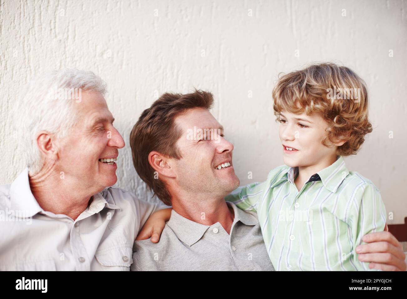 He brings them so much joy. a handsome man sitting with his father and his son. Stock Photo